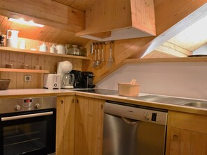 Eine kompakte Küche mit Holzschränken, einem Geschirrspüler von Bosch, einer Kaffeemaschine und einem Toaster.