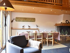 A cozy living room with a fireplace, a dining area with striped tablecloths, and a modern sofa. - Apartment at the slopes - 8 guests (Méribel)