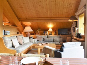 A cozy living room with a wooden ceiling, a sofa set, a coffee table, and a television. - Apartment at the slopes - 8 guests (Méribel)