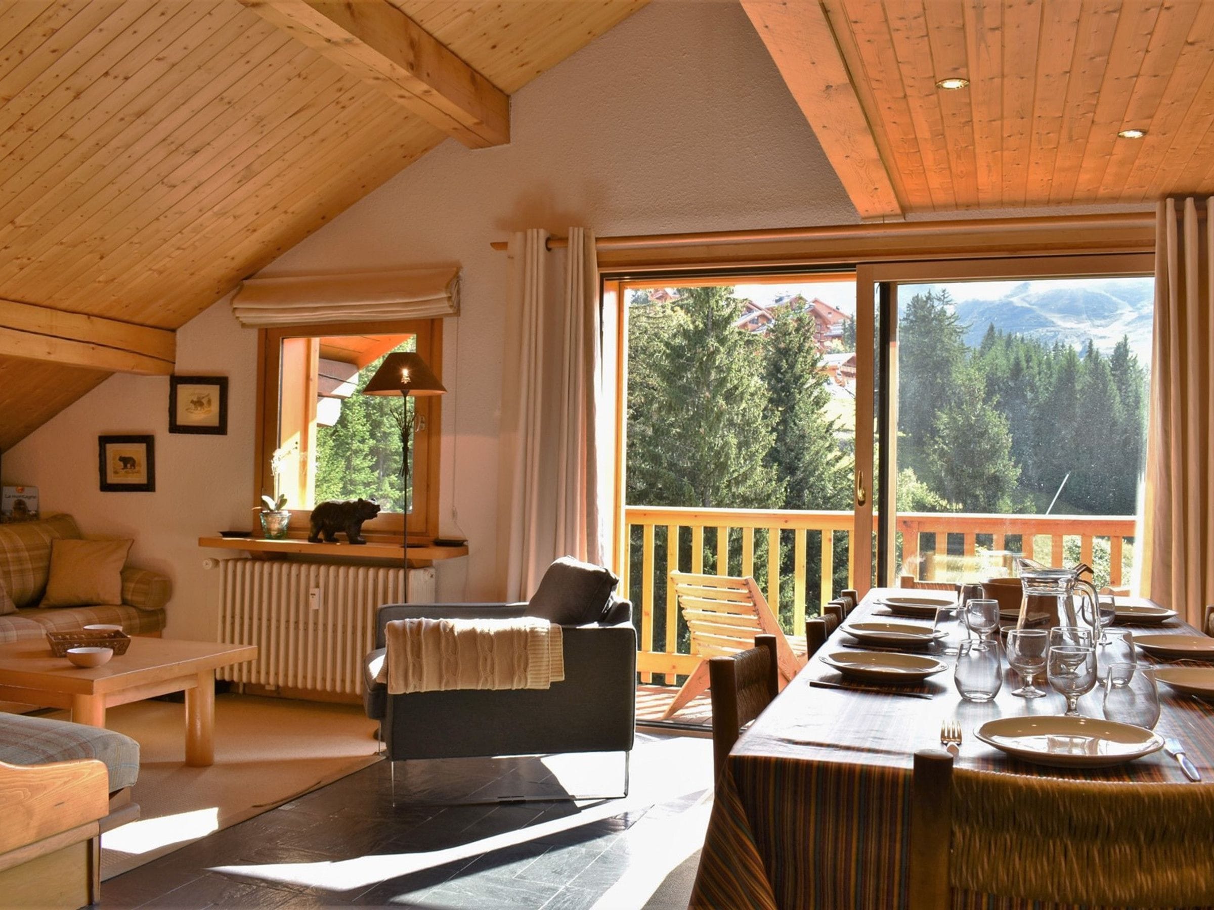 A cozy room with a dining area, a sofa, a table, and a view of the outdoors.