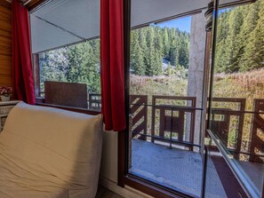 Ein Zimmer mit Blick auf bewaldetes Gebiet durch ein großes Fenster mit roten Vorhängen.