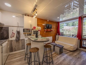 Eine moderne Küche mit Kochinsel, Barhocker, Essbereich mit Sofa und Wand-Fernseher.