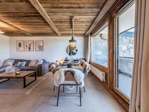 A cozy interior with a dining table, sofa, and large windows offering a view. - New apartment near slopes - 4 guests (Courchevel)