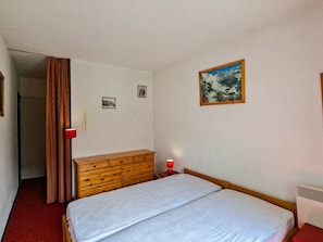 A bedroom with a bed, a dresser, a heater, and a painting on the wall. - Apartment in Flaine Forêt - 6 guests (Flaine)