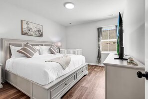 Une chambre à coucher avec un lit, une table de chevet, une lampe et un téléviseur posé sur un meuble.