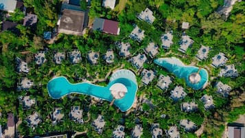 An aerial view of a resort with multiple bungalow-style accommodations, a central swimming pool, and surrounding greenery.