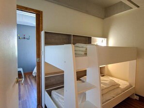 A bunk bed room with a wooden floor, a door, and a wall-mounted shelf with items. - Renovated apartment between slopes and shops - 6 guests (Flaine)