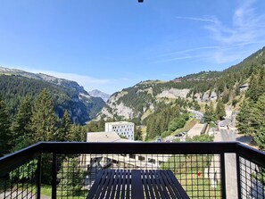 A mountain view from a balcony with a metal railing, overlooking a valley with buildings and a road. - Renovated apartment between slopes and shops - 6 guests (Flaine)