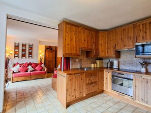 Eine moderne Küche mit Holzschränken, einem eingebauten Backofen und einer Mikrowelle.