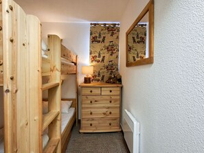 Ein schmales Zimmer mit einem Etagenbett, einem Schminktisch und einem Spiegel an der Wand.