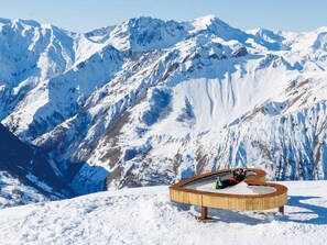 A wooden bench with a person relaxing, surrounded by snow-covered mountains. - Calm apartment near the slopes (Méribel)