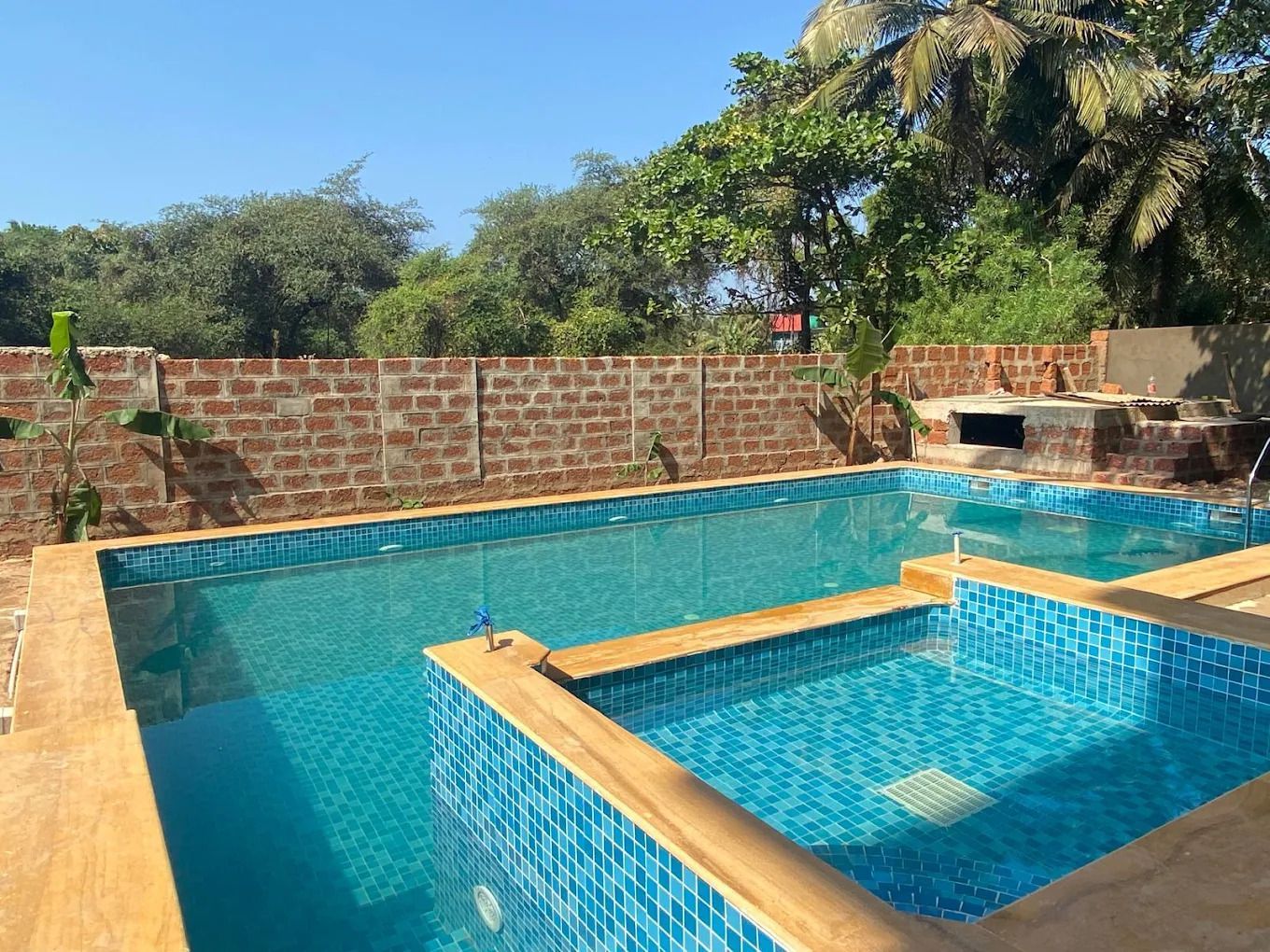 Ein rechteckiger Swimmingpool mit blauen Fliesen und einer Holzdeckumrandung.