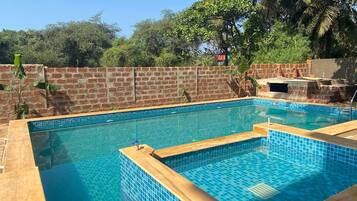 Ein rechteckiger Swimmingpool mit blauen Fliesen und einer Holzdeckumrandung.