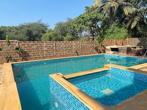 Una piscina rectangular amb rajoles blaves i un voreig de fusta.