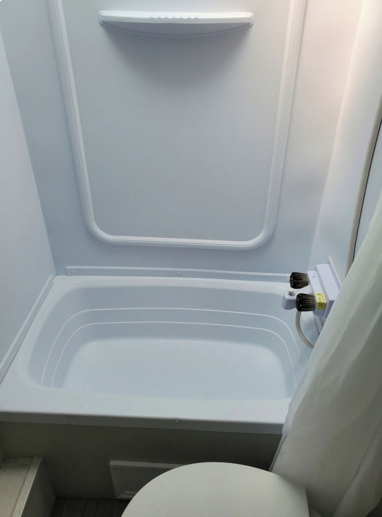Een compacte, afgesloten badkamer met een bad, toilet en douche.