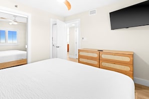 A bedroom with a bed, a wardrobe, a television, and a door leading to another room. - Vitamin Sea, Beachfront Condo, Gulf Views, Pool, Fire Pit (Santa Rosa Beach)