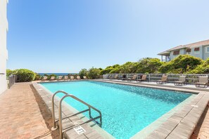 A rectangular swimming pool with a metal ladder, surrounded by lounge chairs and a white building. - Vitamin Sea, Beachfront Condo, Gulf Views, Pool, Fire Pit (Santa Rosa Beach)