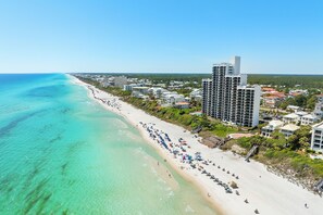 A coastal cityscape with a beach, high-rise buildings, and clear turquoise waters. - Vitamin Sea, Beachfront Condo, Gulf Views, Pool, Fire Pit (Santa Rosa Beach)