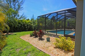Un jardin avec une piscine, une terrasse couverte et une grande variété de plantes.