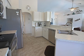 A modern kitchen with a refrigerator, dishwasher, and a double sink. - Tranquil Retreat with Extended Lanai #313 (Rotonda West)