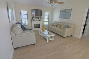 A living room with a fireplace, a sofa, a coffee table, and a ceiling fan. - Canal-Side: Pool Home in Rotonda West #61 (Rotonda West)