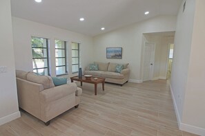 A spacious living room with a beige sofa, a coffee table, and a painting on the wall. - Canal-Side: Pool Home in Rotonda West #61 (Rotonda West)