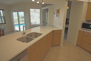 A kitchen with a double sink, wooden cabinets, and a dishwasher. - Waterfront Oasis: Rotonda West Canal #202 (Rotonda West)