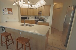 A modern kitchen with a central island, stainless steel appliances, and wooden cabinets. - Waterfront Oasis: Rotonda West Canal #202 (Rotonda West)