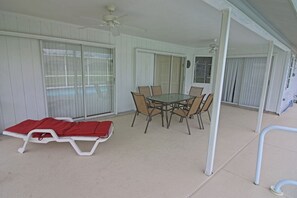 A covered patio with a table and chairs, a lounge chair, and a ceiling fan. - Waterfront Oasis: Rotonda West Canal #202 (Rotonda West)