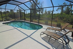 A swimming pool with a clear view of the surrounding landscape, including trees and a fence. - Sunshine Retreat: SW facing pool, 2 En-Suites #36 (Rotonda West)