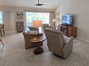 A living room with a sofa, armchair, coffee table, television, and a ceiling fan. - Sunshine Retreat: SW facing pool, 2 En-Suites #36 (Rotonda West)