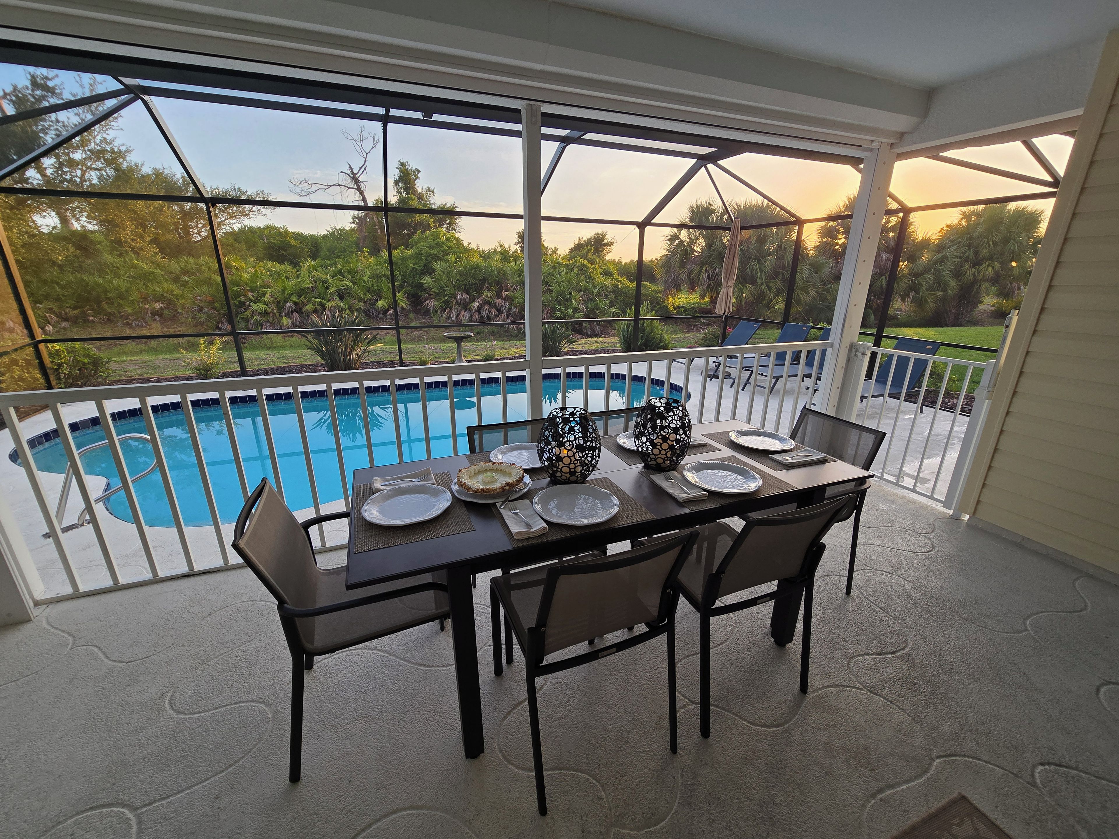 Comedor con una mesa preparada para cuatro, con vistas a una piscina.