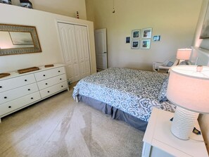 A bedroom with a bed, dresser, mirror, and wall-mounted pictures. - Waterfront Haven: SW Facing Pool and Spa #10 (Rotonda West)