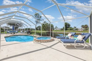 Et udendørs poolområde med tag, liggestole og jacuzzi.