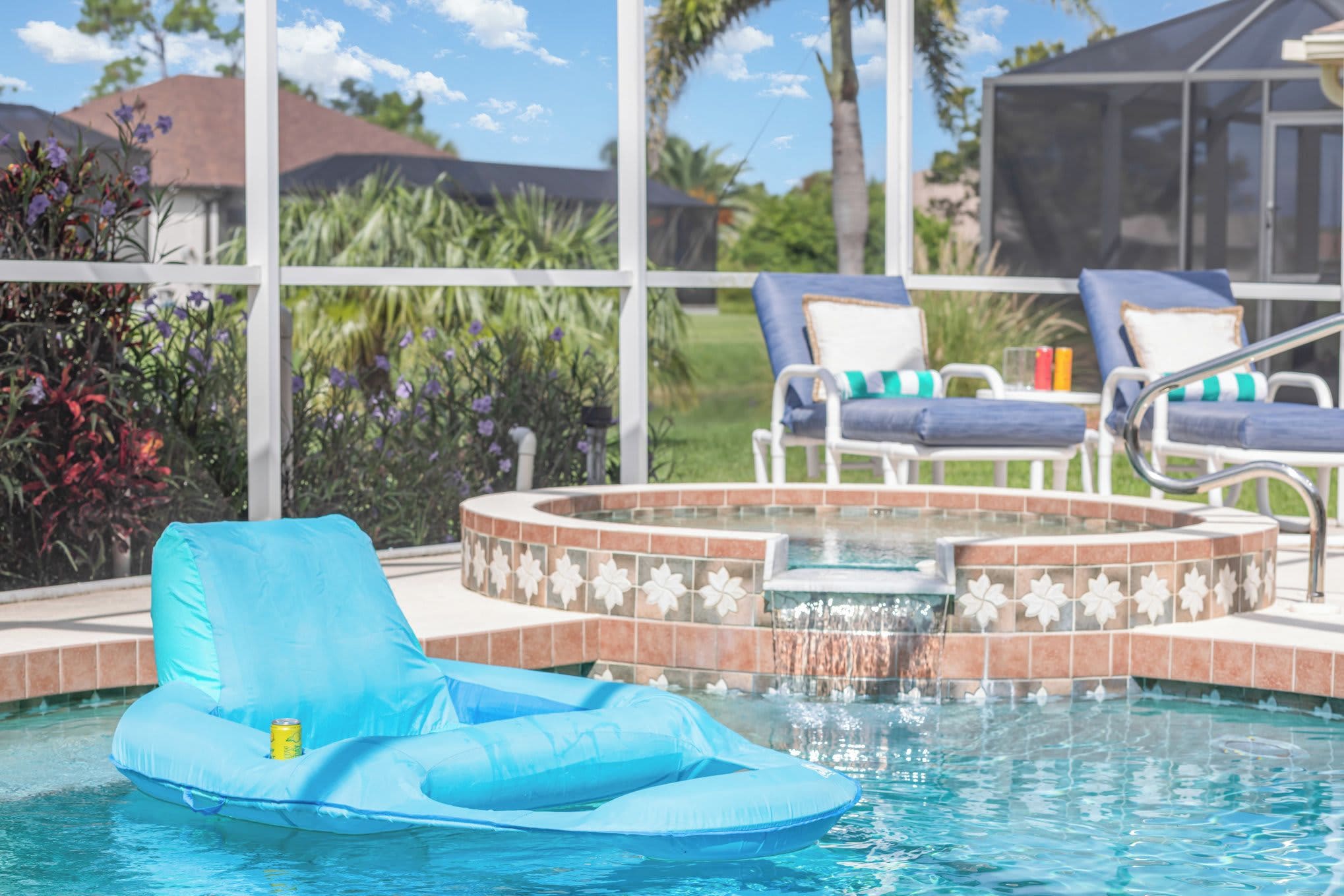 A pool area with a hot tub, lounge chairs, and a blue inflatable float.