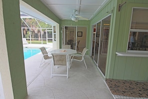 A covered patio with a pool, a table with chairs, and a ceiling fan. - Serene West Facing Pool -Rotonda West #15 (Rotonda West)