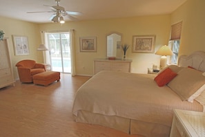 A bedroom with a bed, a chair, a dresser, a ceiling fan, and a window. - Serene West Facing Pool -Rotonda West #15 (Rotonda West)