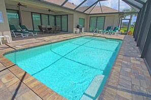 A swimming pool with a tiled deck, lounge chairs, and a covered patio area. - Rotonda River Villa pool home #1125 (Rotonda West)