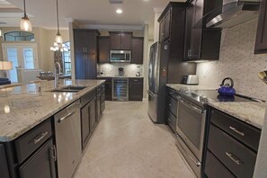 Una cucina moderna con mobili scuri, elettrodomestici in acciaio inossidabile e un piano di lavoro in granito.