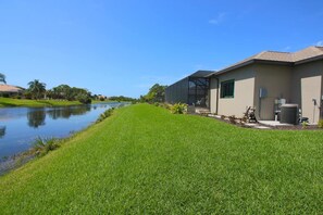 A residential property with a grassy lawn, a body of water, and a modern building with a flat roof. - Rotonda River Villa pool home #1125 (Rotonda West)