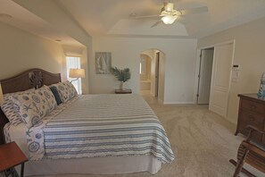 A bedroom with a bed, a nightstand, a ceiling fan, and a door leading to a bathroom. - Spacious Pool and Expansive Canal Views #811 (Rotonda West)
