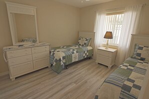 A bedroom with a bed, dresser, nightstand, lamp, and a window with curtains. - Spacious Pool and Expansive Canal Views #811 (Rotonda West)