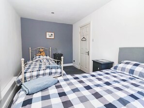 A bedroom with a bed, bedside table, and a door. - Winksey Cottage (Harrogate)
