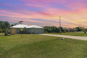 A residential area with a single-story house, a paved driveway, and a grassy lawn. - This house is a 2 bedroom(s), 2 bathrooms, located in Rotonda West, FL. (Rotonda West)