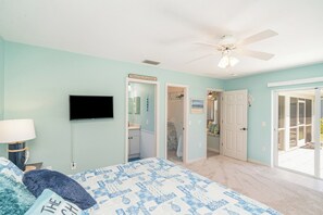 A bedroom with a bed, a television, a ceiling fan, and a door leading to a bathroom. - This house is a 2 bedroom(s), 2 bathrooms, located in Rotonda West, FL. (Rotonda West)