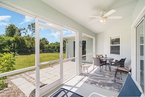 A covered patio area with a ceiling fan, outdoor seating, and a view of a grassy yard. - This house is a 2 bedroom(s), 2 bathrooms, located in Rotonda West, FL. (Rotonda West)