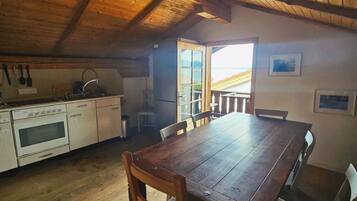 Interior de madera con cocina, mesa de comedor y sillas.