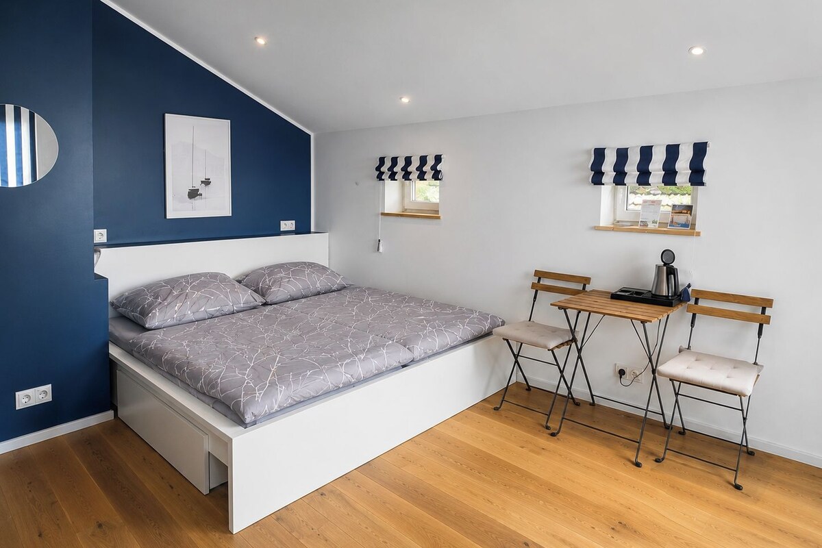 A bedroom with a bed, a desk, and chairs.