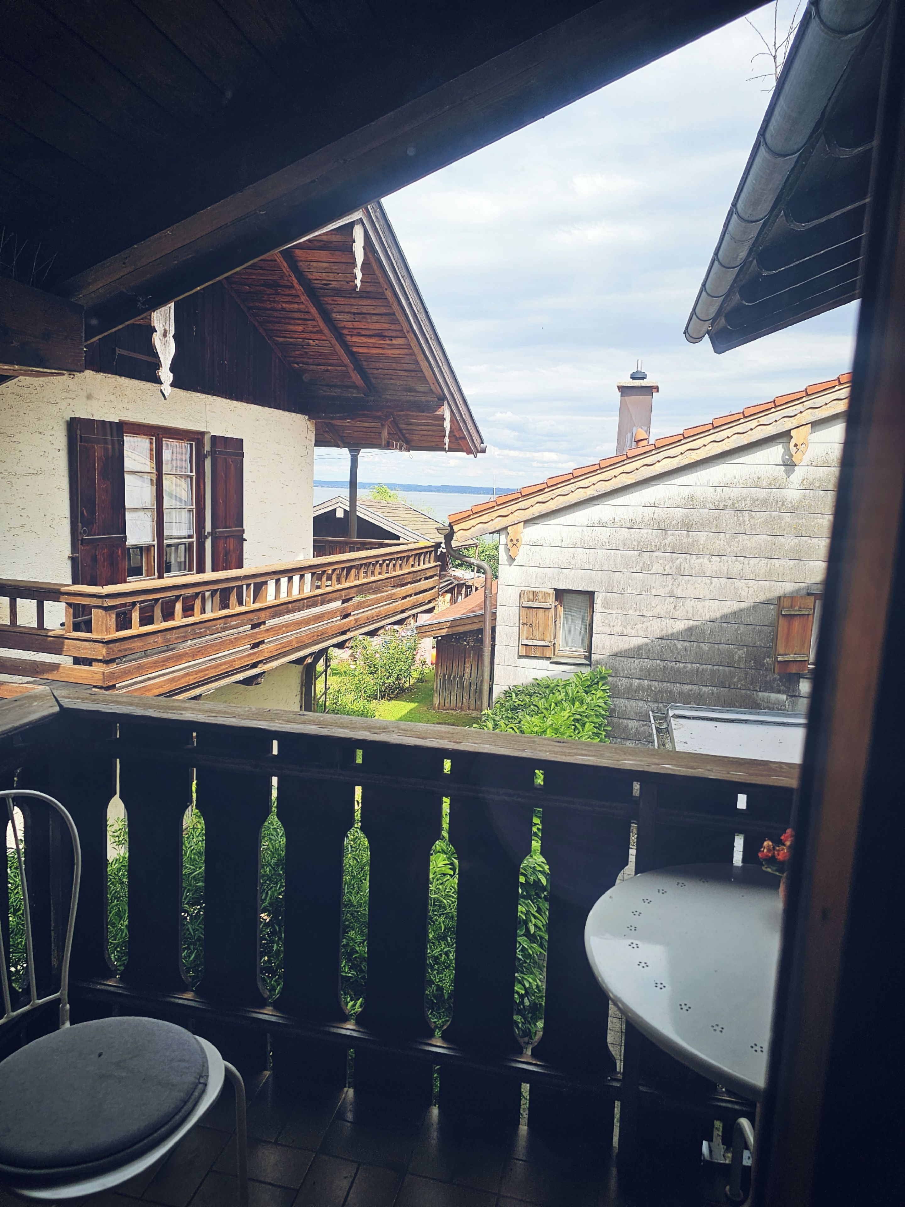 A balcony with a wooden railing, a table, and a chair.