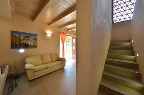 Ein Wohnzimmer mit einer Couch, einem Gemälde, einer Lampe und einer Treppe.